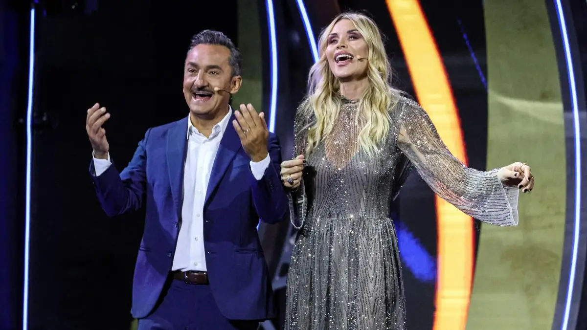 Palco televisivo con fiori e musicisti durante uno spettacolo dedicato alla musica italiana