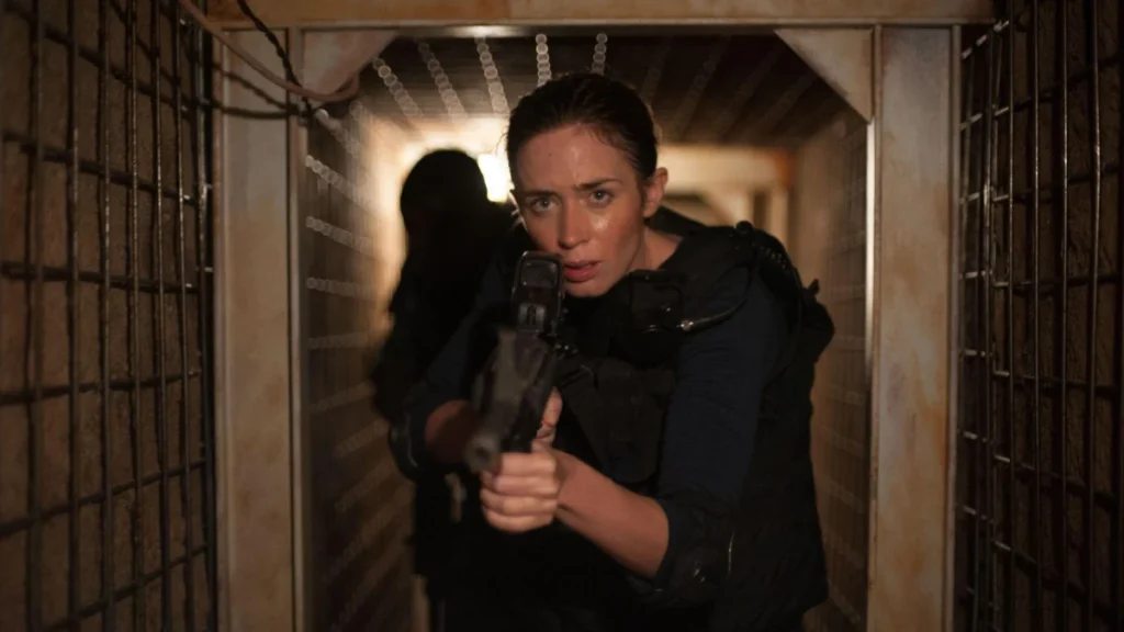 Emily Blunt avanza armata in un passaggio stretto in una scena di Sicario